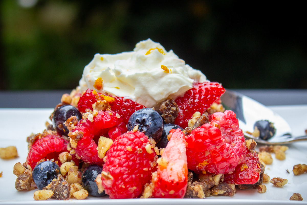 berries with nut mixture topped with whipped cream on plate.