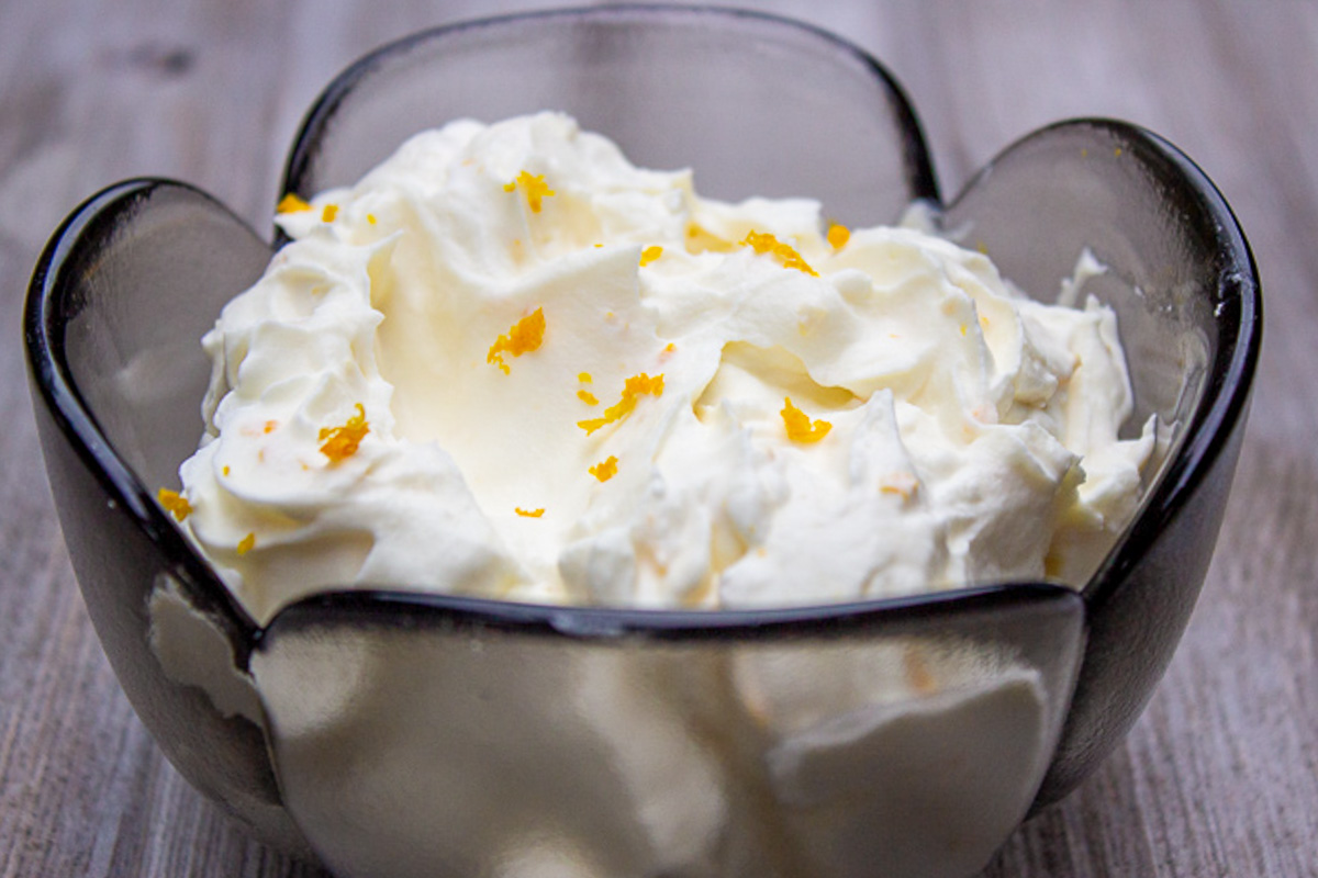 whipped cream with orange zest in glass bowl.
