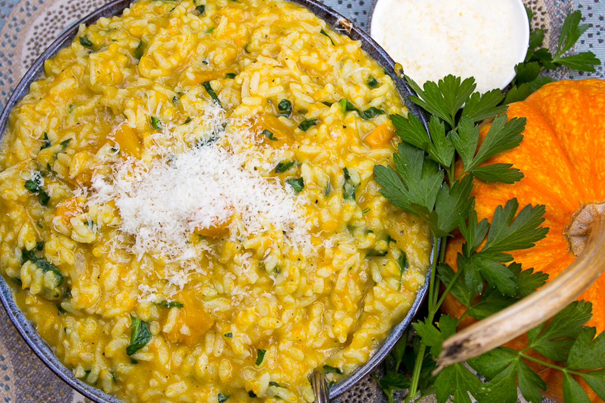 pumpkin risotto with grated parmesan in bowl beside a pumpkin.