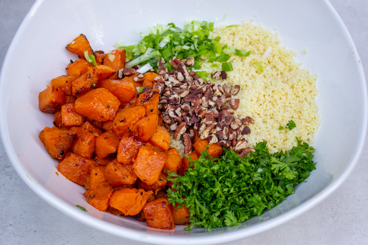 all prepared pumpkin couscous salad ingredients laid out in serving bowl, not yet mixed.