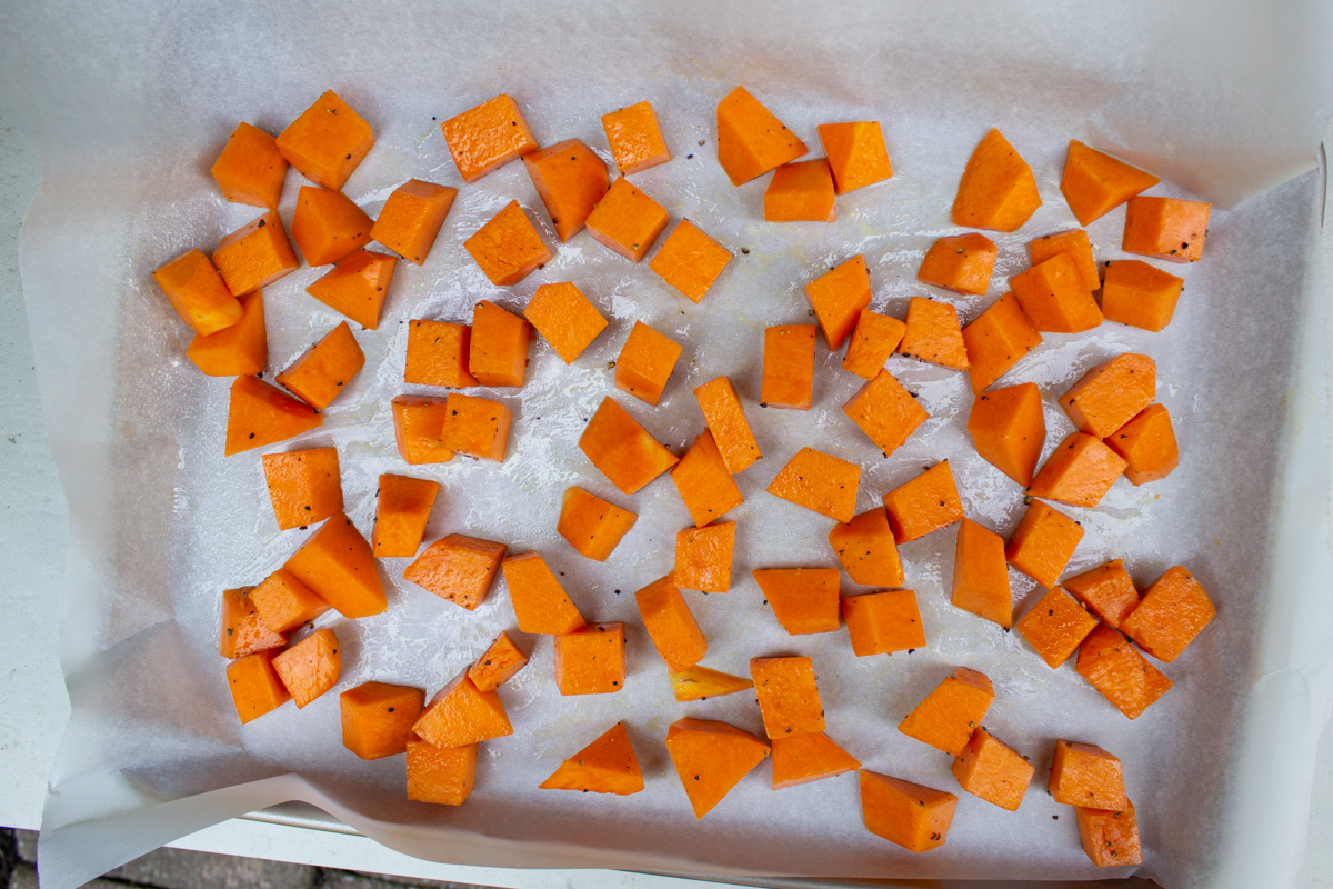 diced seasoned pumpkin on baking tray lined with parchment.