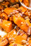candied sweet potatoes with pecans in white bowl.