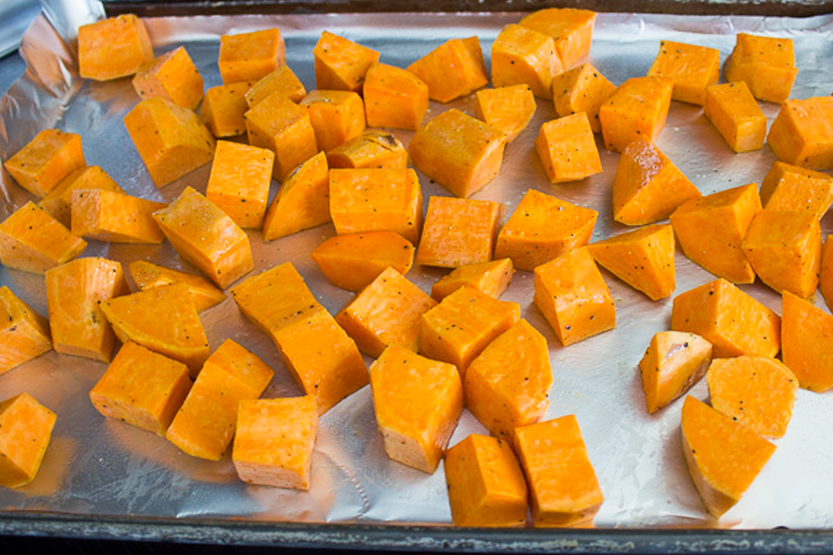 seasoned raw sweet potato cubes on baking sheet.