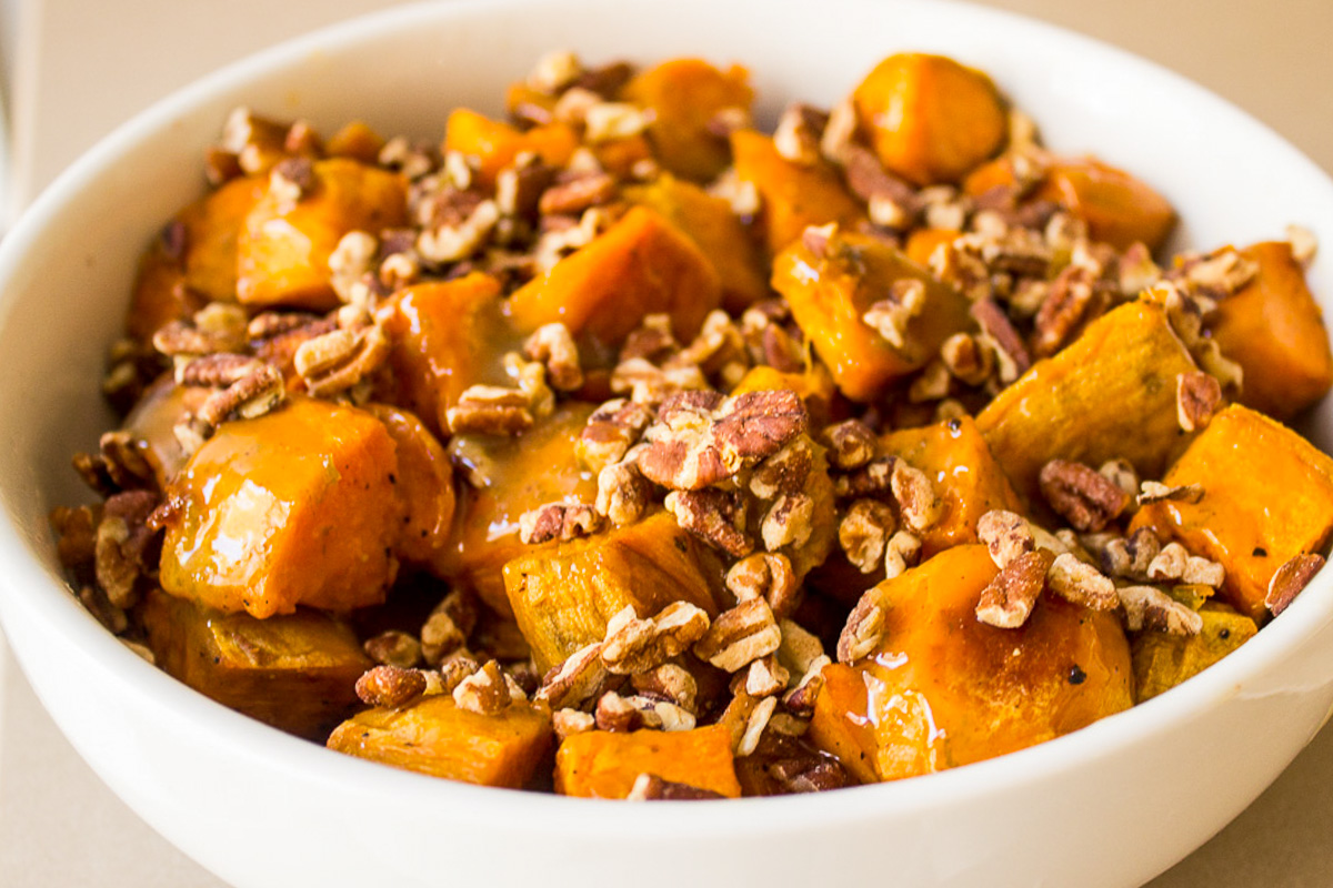 candied sweet potatoes with pecans in white bowl.