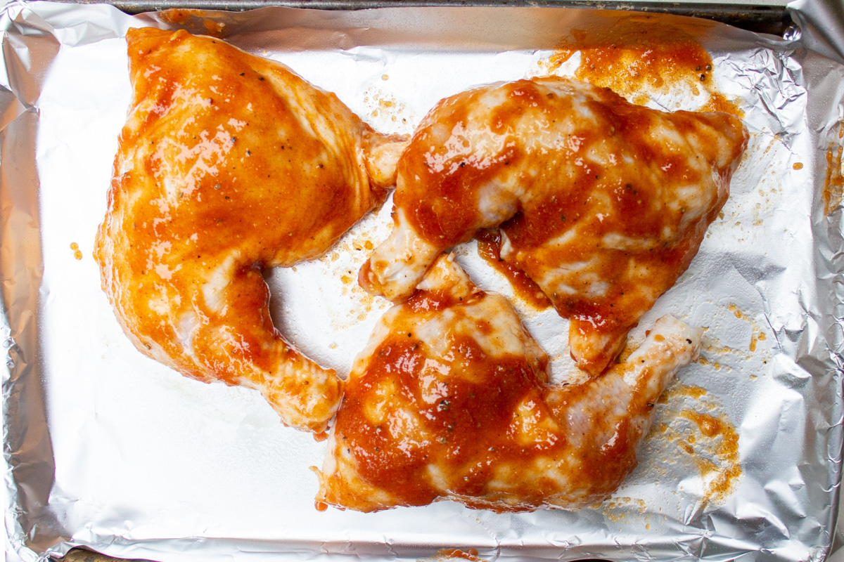 chicken legs brushed with glaze on foil-lined pan.