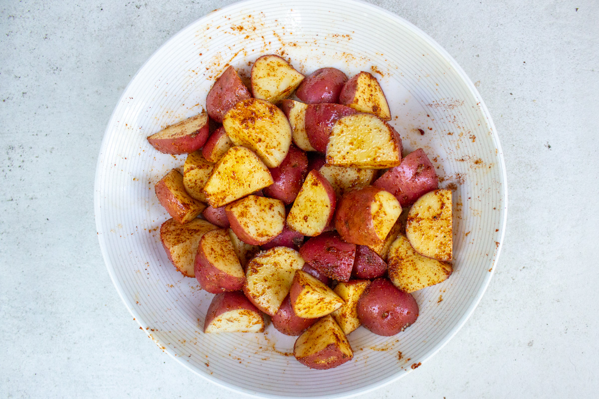 quartered potatoes seasoned in a bowl.