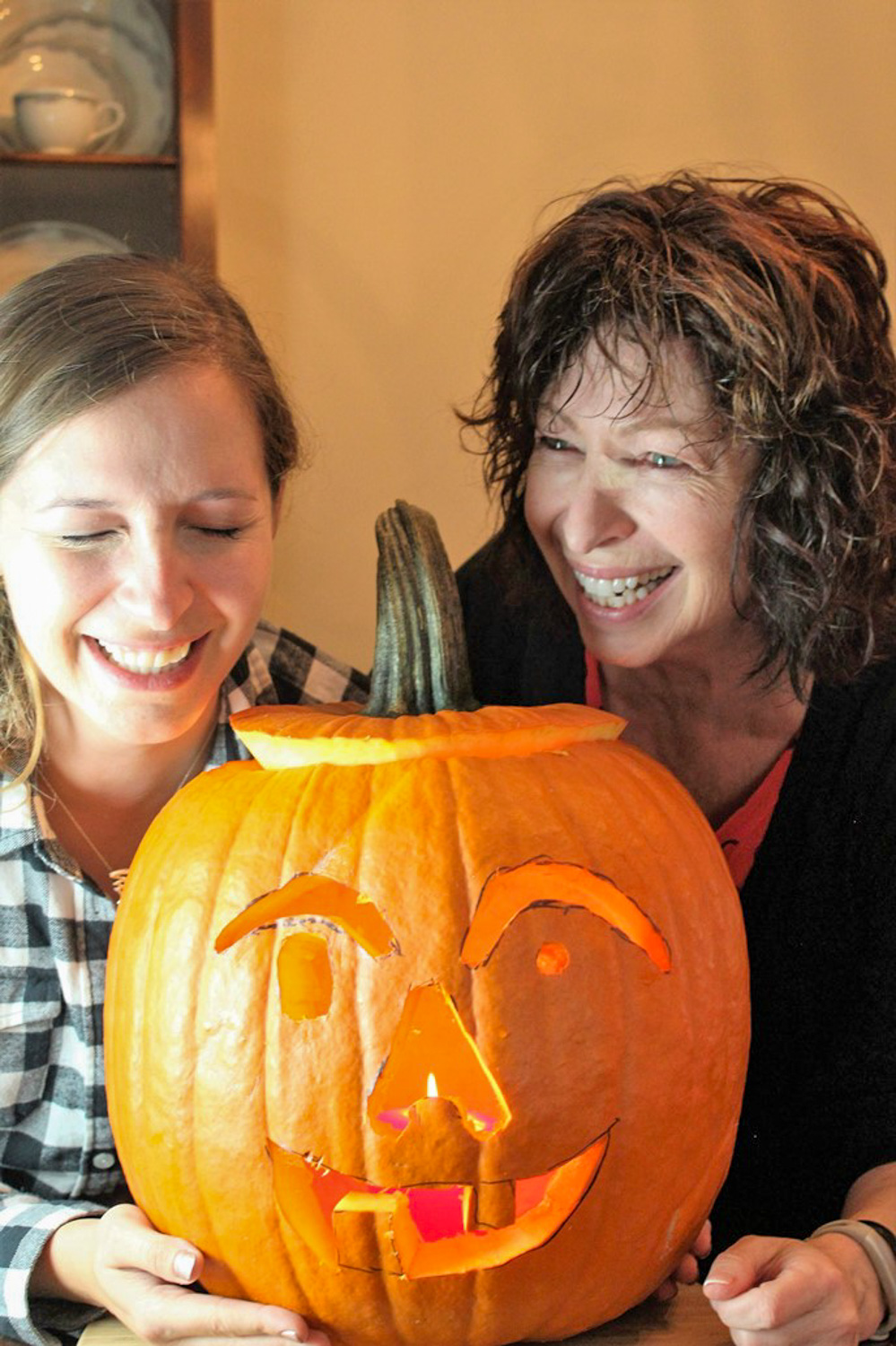 Jenna and Cheryl laughing over their carved pumpkin.