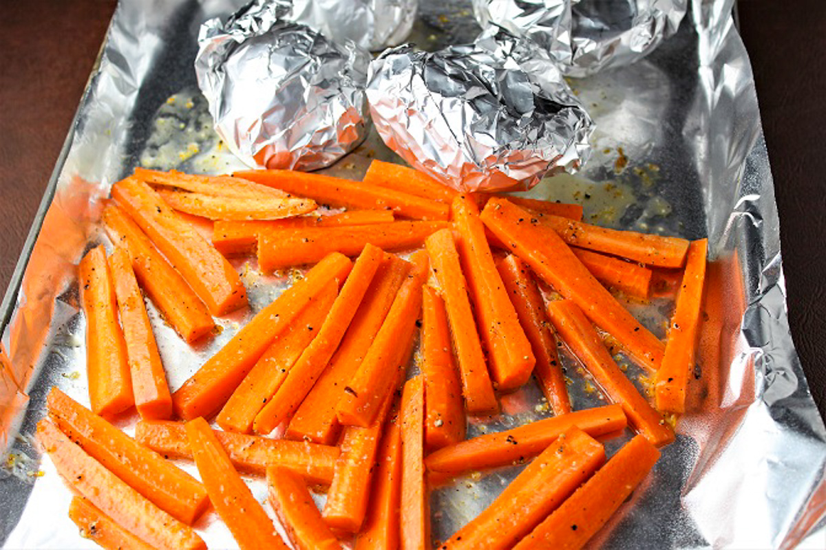 raw carrot sticks and foil wrapped beets on sheet pan.