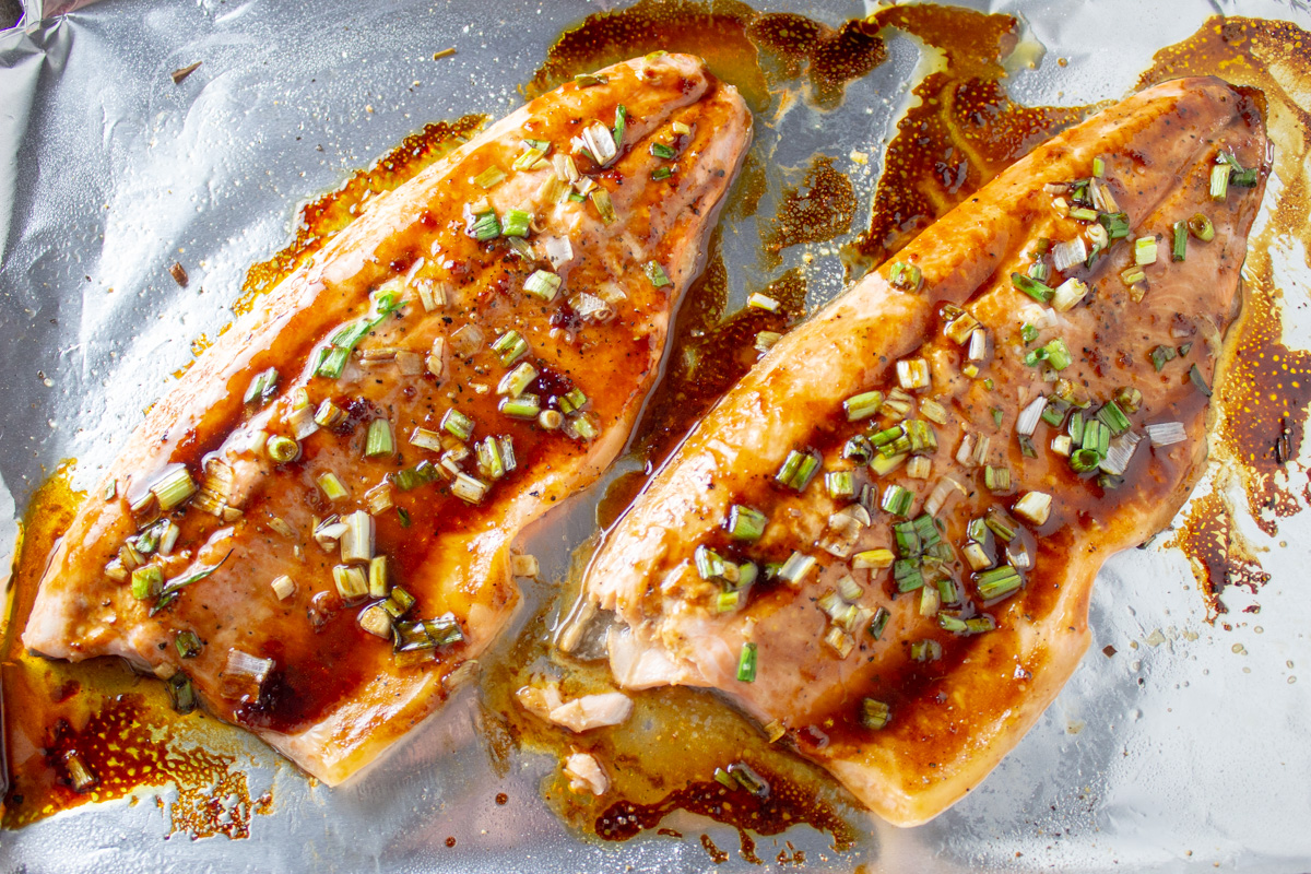 two baked glazed trout filets on foil lined pan.