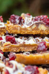 stack of toffee bars with graham crackers, nuts, cranberries and chocolate.