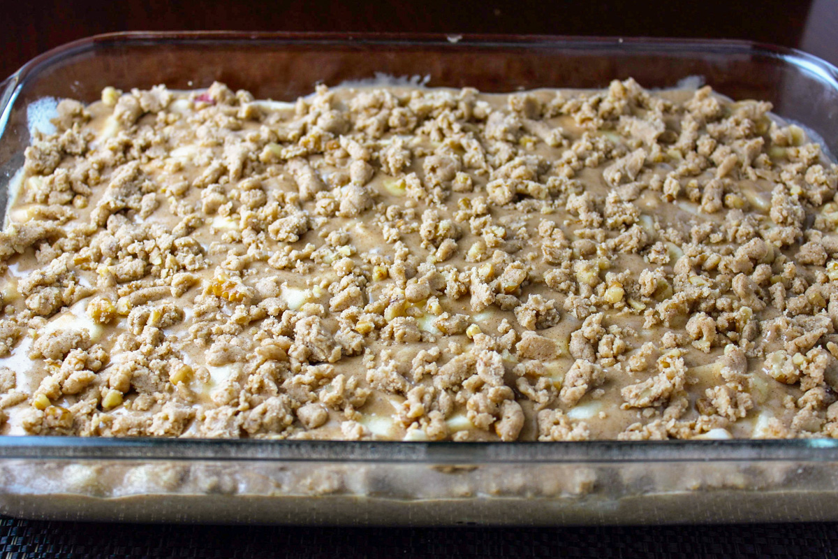 batter with apples and crumble topping in cake pan.