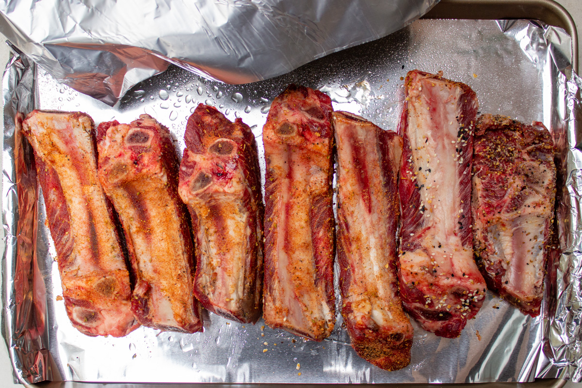 seasoned ribs meat side down on foil line baking sheet before baking.