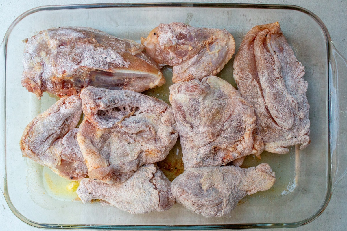 raw chicken pieces dusted in flour, skin side down in casserole dish.