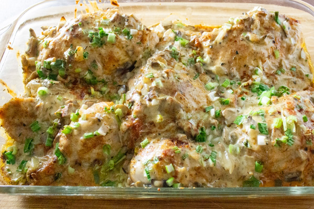 baked chicken in casserole dish with creamy mushroom sauce on top.