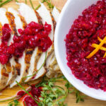 bowl with cranberry relish beside slide turkey with the relish on it.