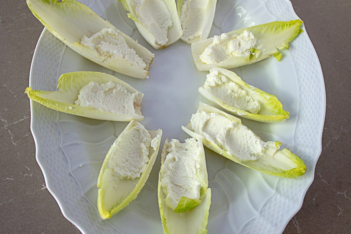 endive leaves with ricotta filler on white plate.
