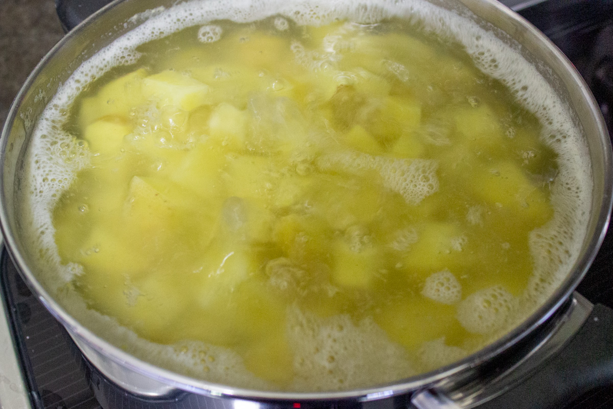 cubed potatoes boiling in salted water in pot.