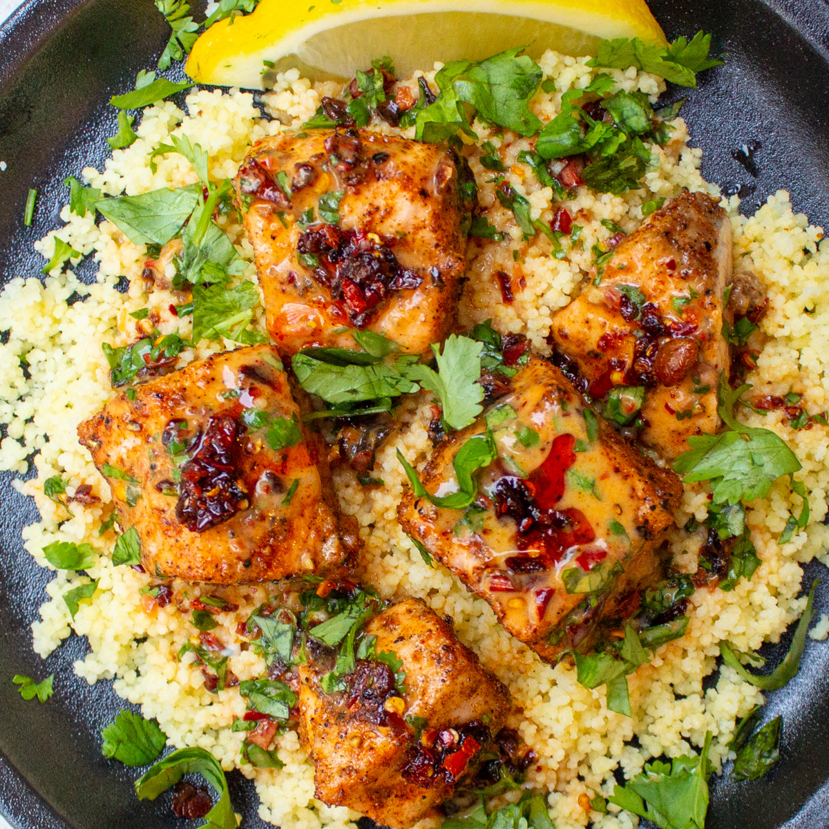5 salmon bites with chili crisp sauce over couscous on plate.