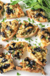 baked olive cheese appetizers on white plate with parsley.