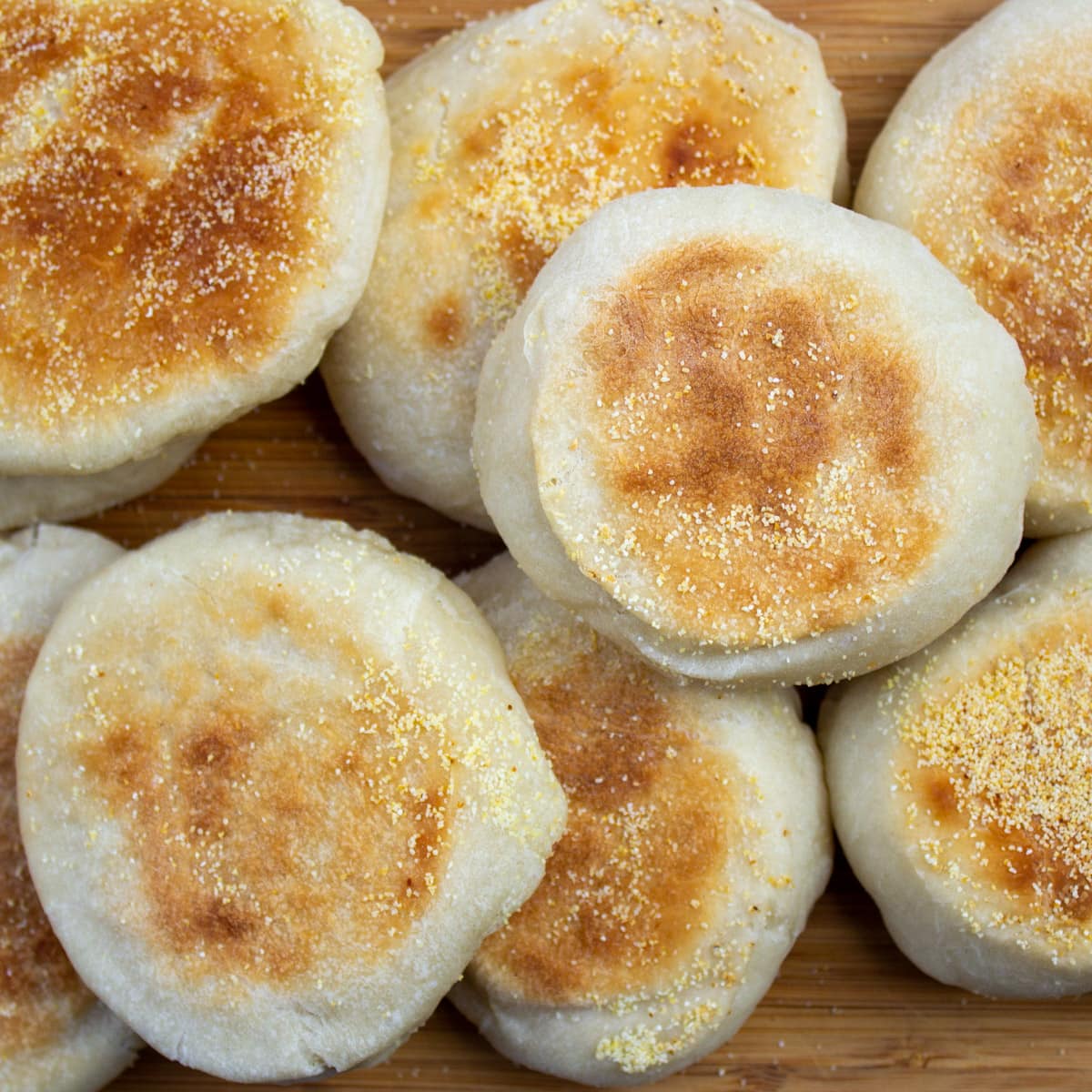 pile of english muffins on cutting board.