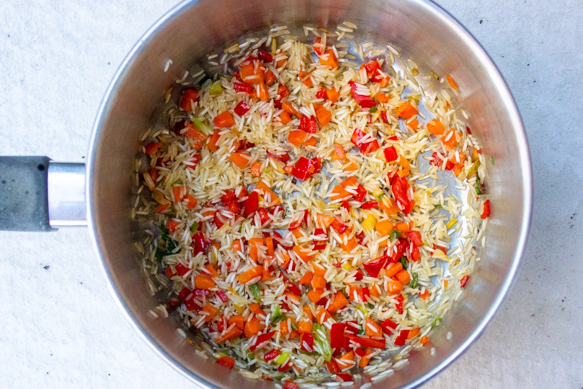 sauteed onions, carrots peppers in pot.