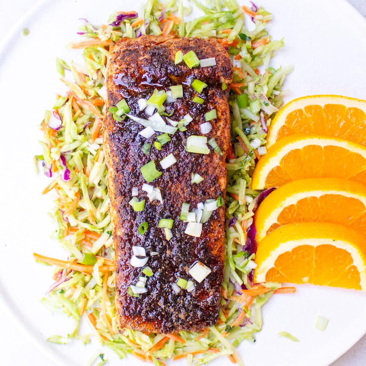 salmon fillet over coleslaw with orange slices on plate.