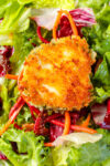 fried crusted goat cheese round on dressed salad greens.
