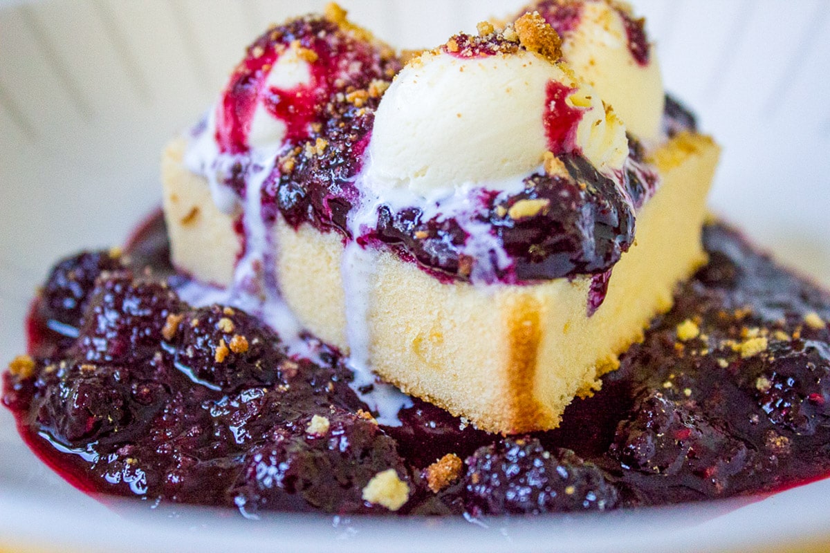 berry sauce over heart shaped pound cake with ice cream on top, garnished with toasted cake crumbs.