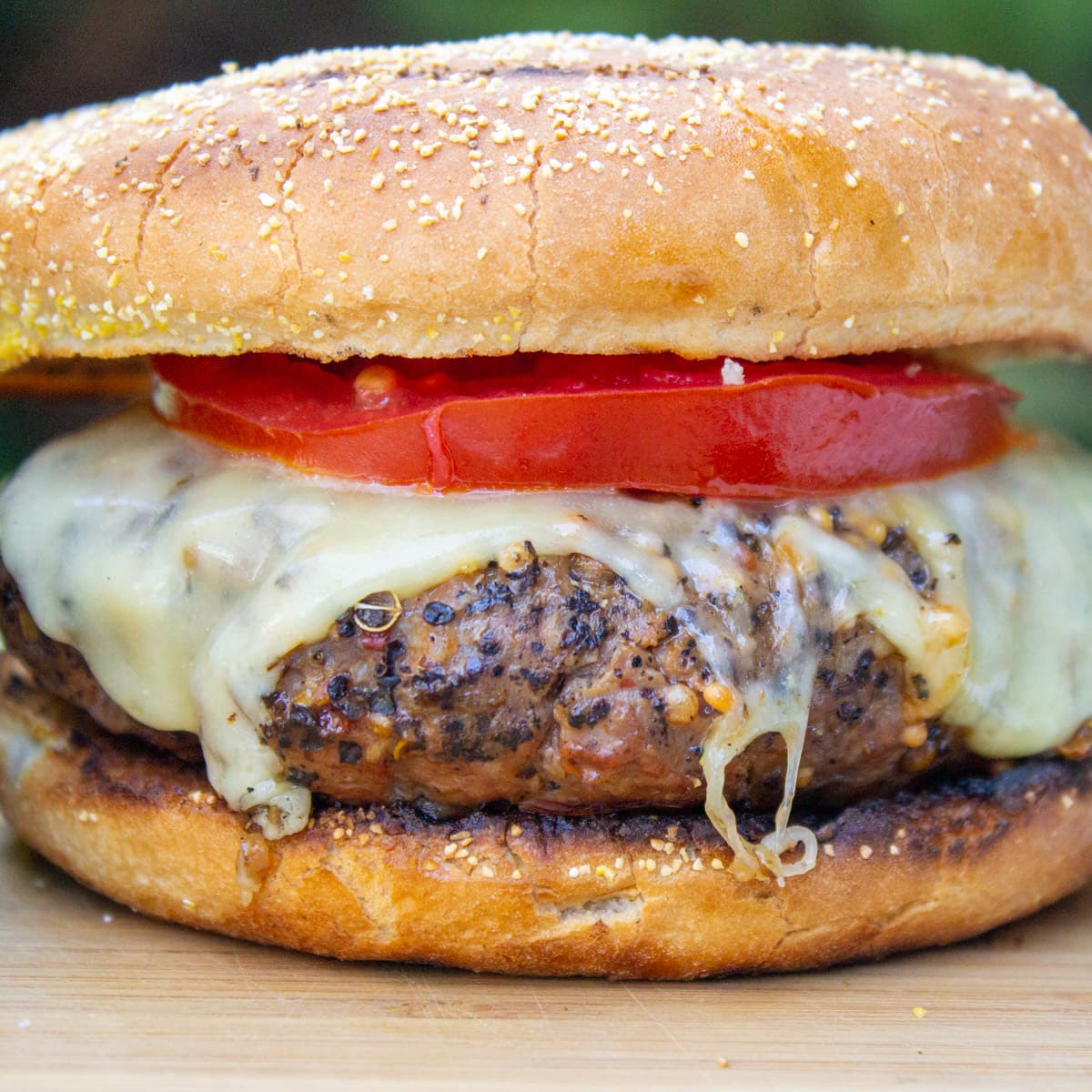 burger topped with cheese and tomato in bun.
