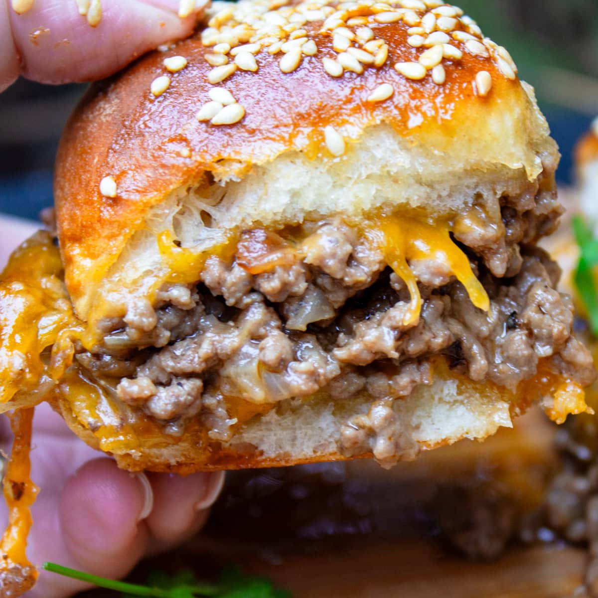 cheeseburger slider held in a hand.