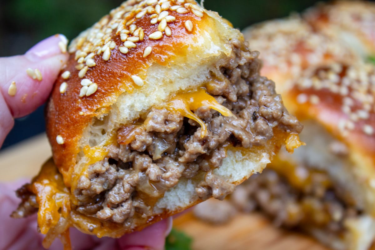 cheeseburger slider held in a hand.