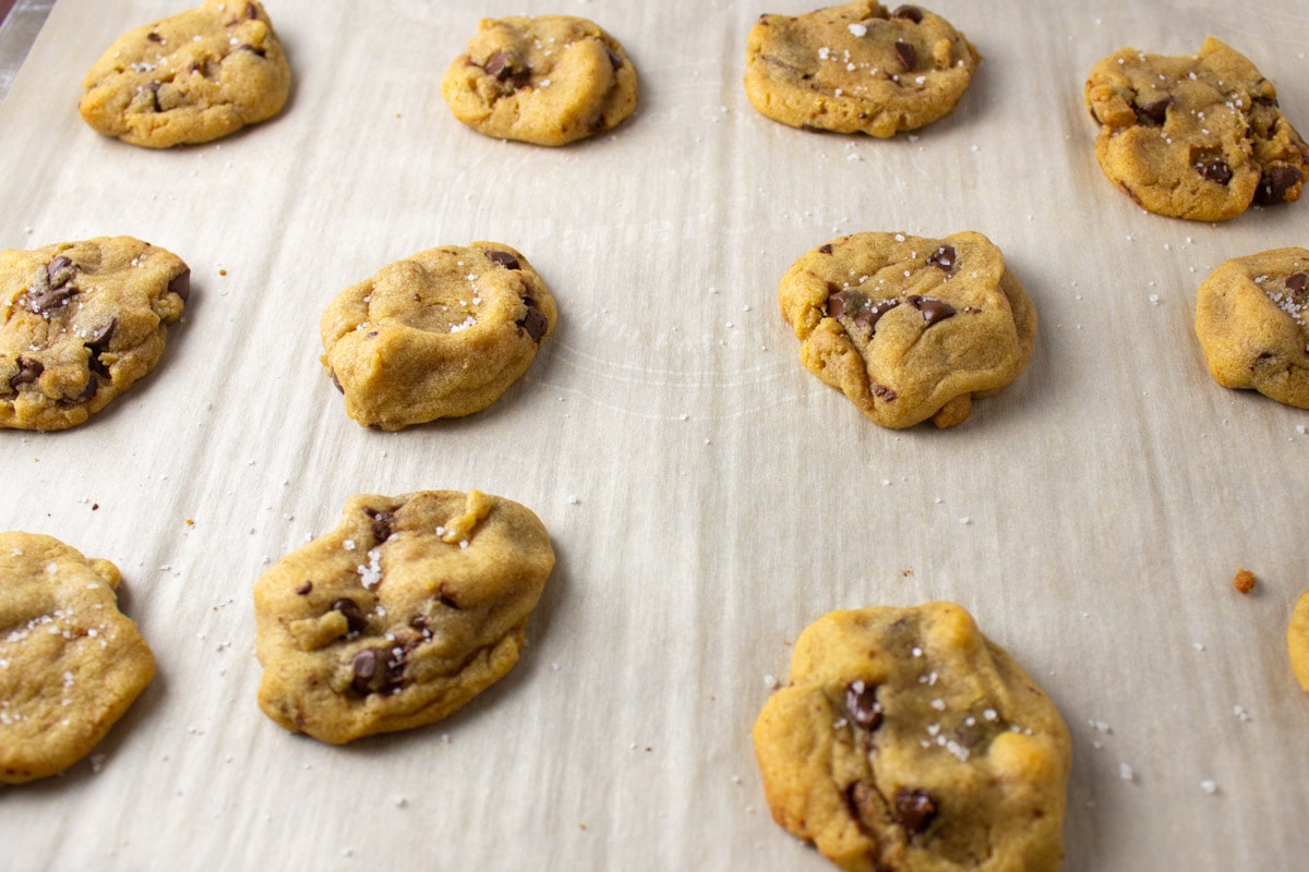 baked chocolate chip cookies on parchment lined sheet pan.