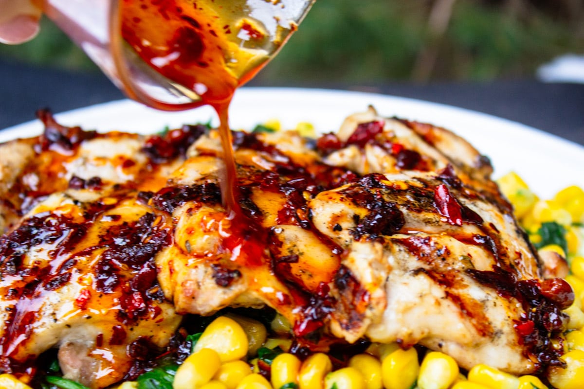 hot honey sauce being drizzled over grilled chicken.