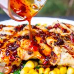 hot honey sauce being drizzled over grilled chicken.