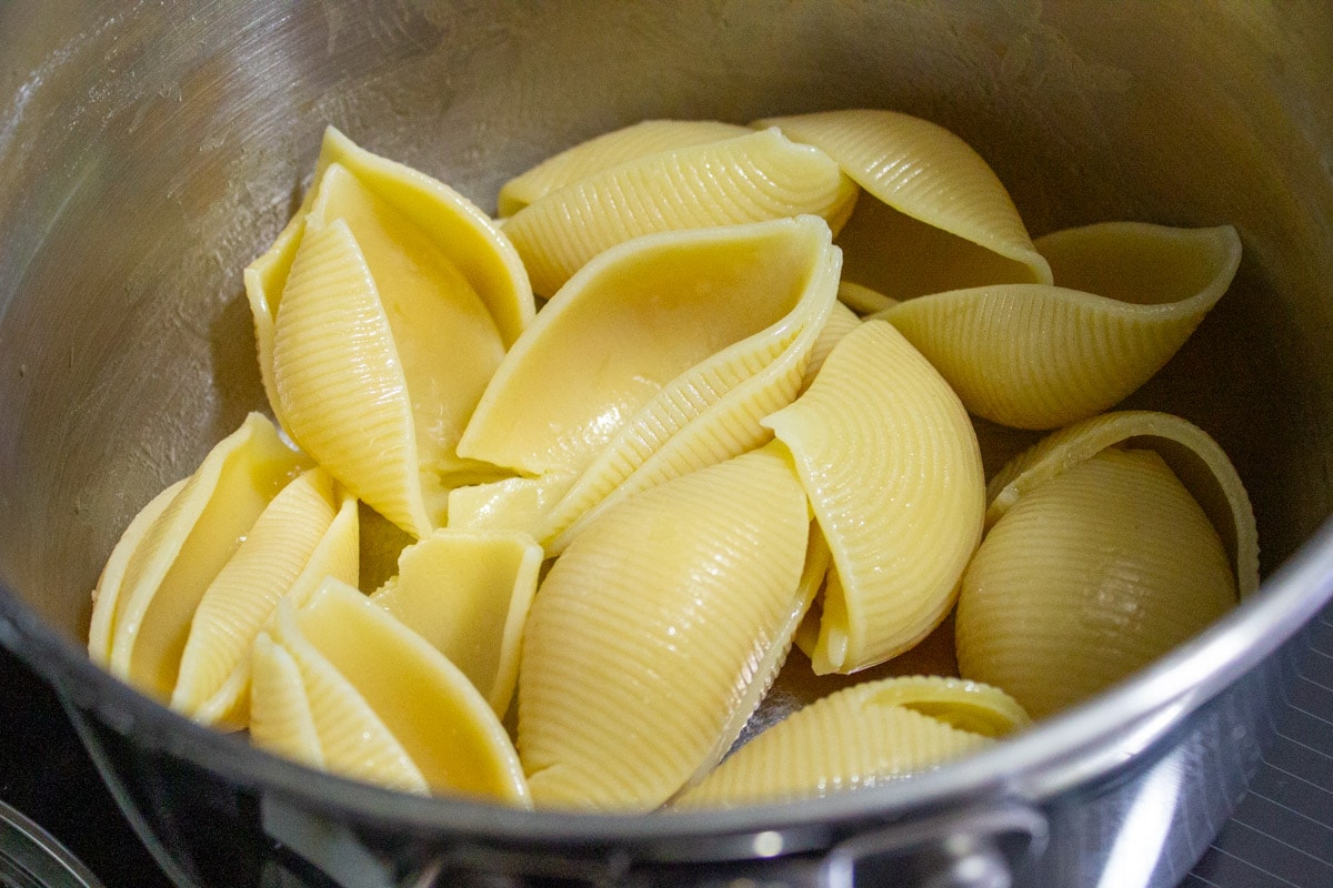 cooked large pasta shells in sieve.