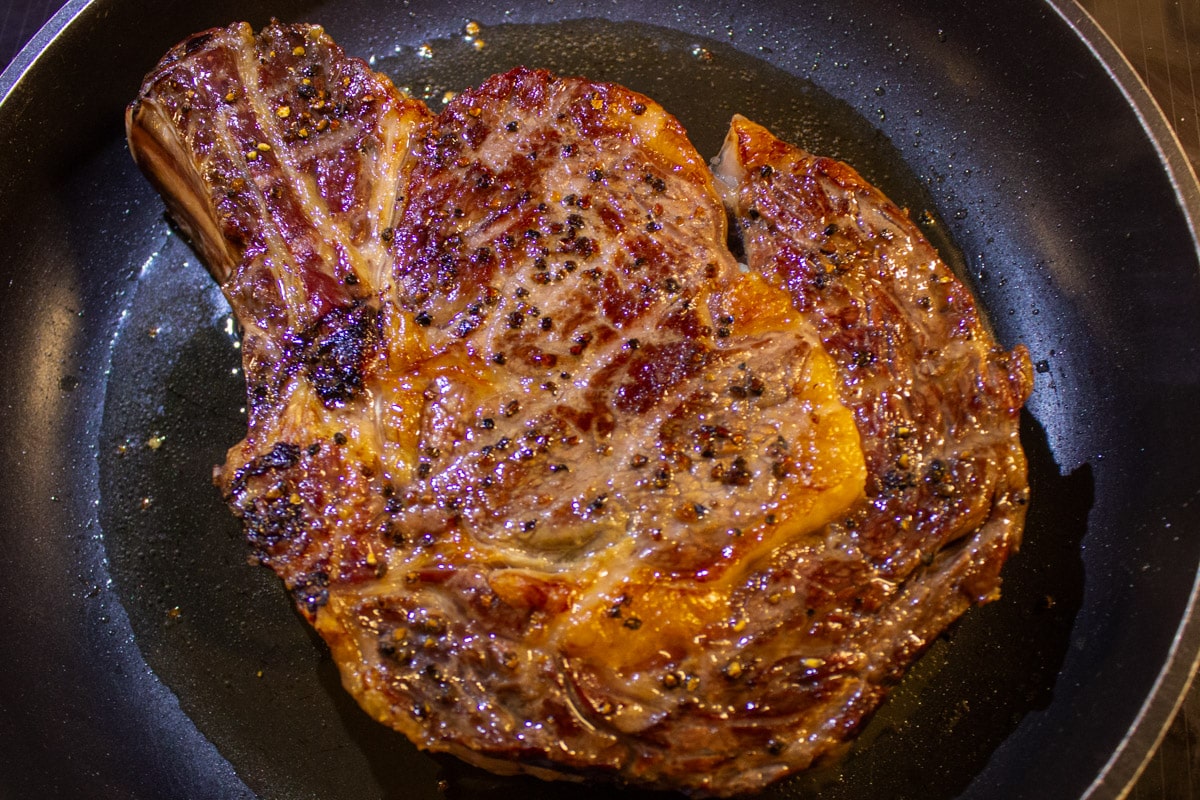 pan seared steak in frying pan with butter.
