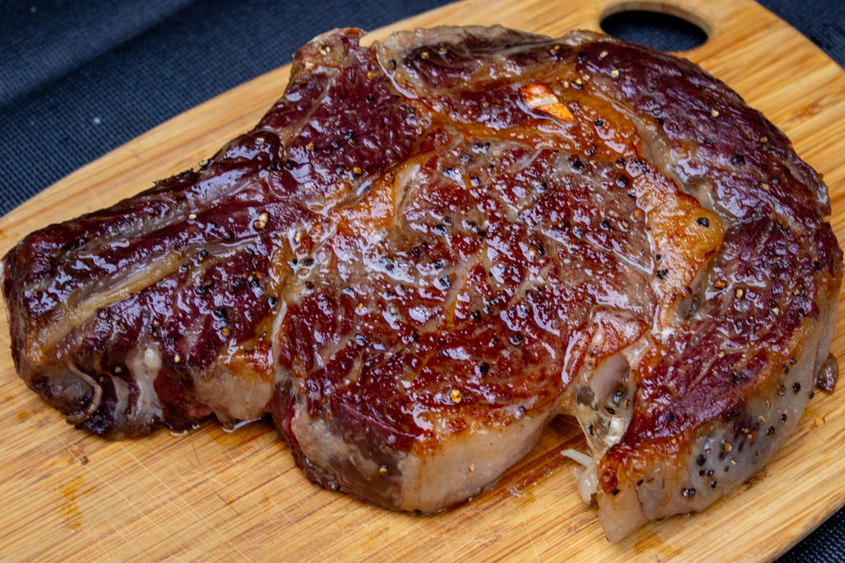 reverse seared ribeye steak resting on cutting board.