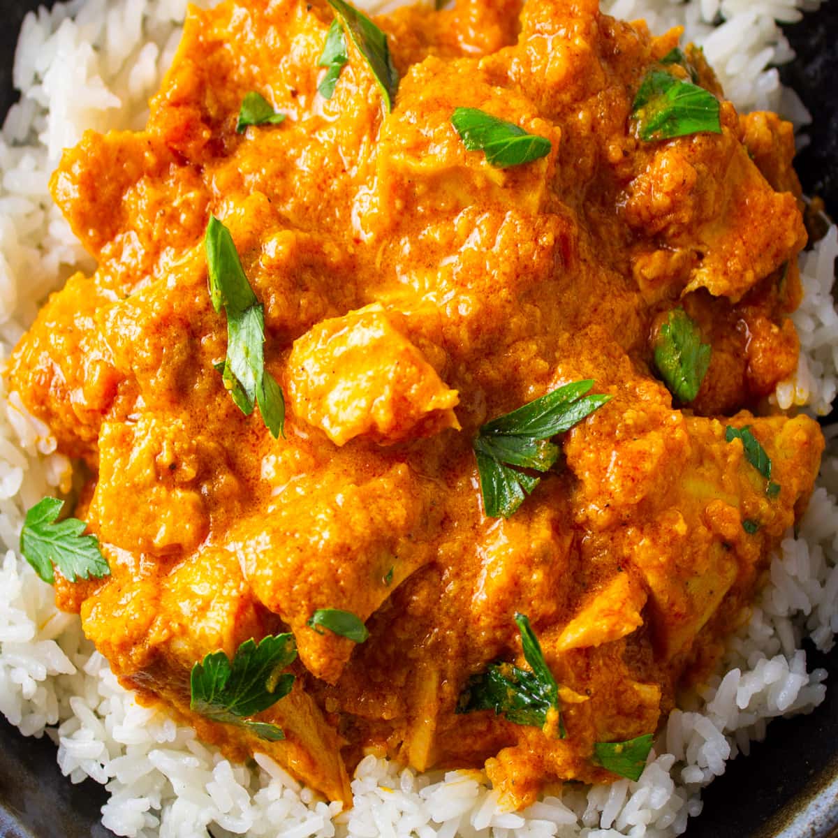 indian butter chicken over rice on plate.