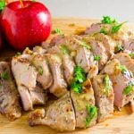 sliced pork tenderloin with mustard sauce on cutting board.