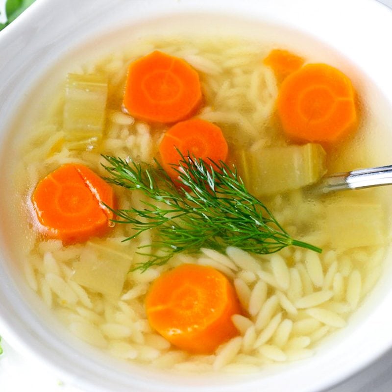 chicken soup with orzo, carrots and dill in bowl.