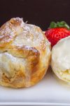 one mini apple pie on plate with ice cream and a strawberry.