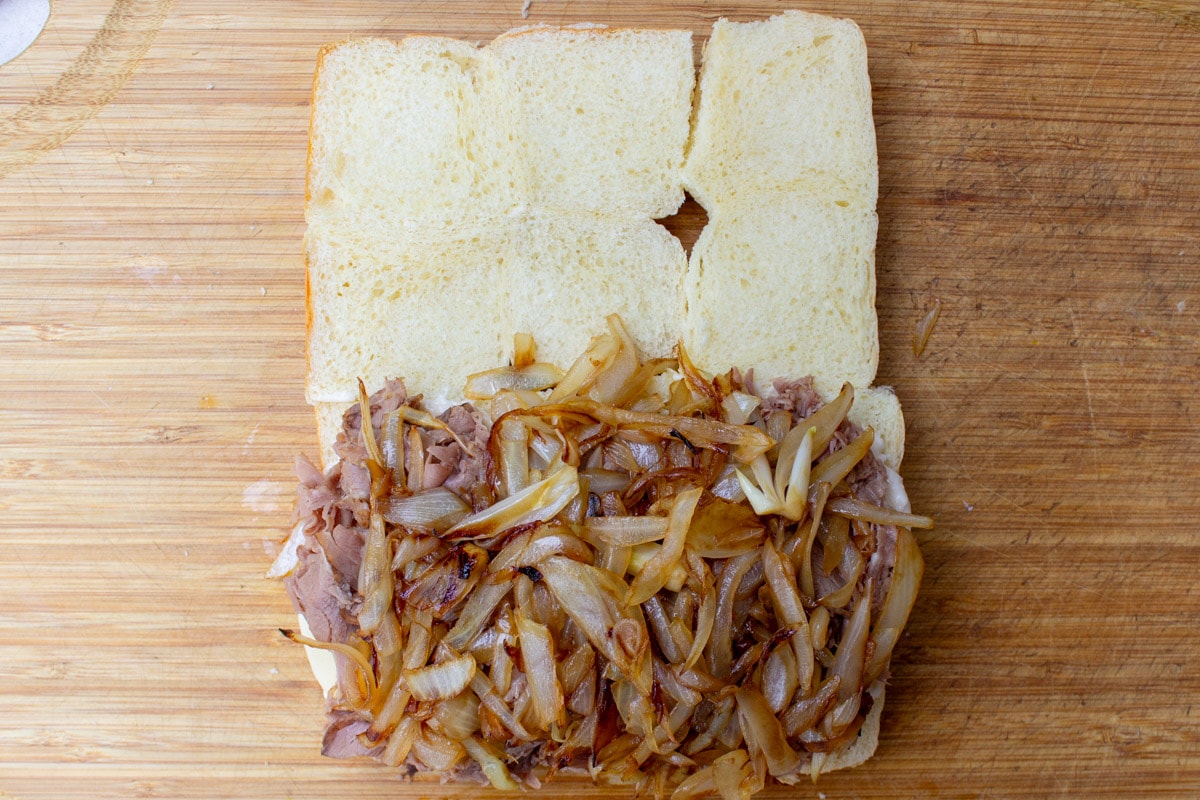 caramelized onions layered on top of beef and cheese on half of buns.