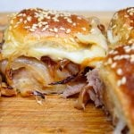 one roast beef slider showing beef, oinos and melty cheese on a cutting board.