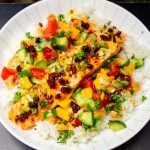 baked salmon topped with chili crisp sauce over white rice and chopped salad.