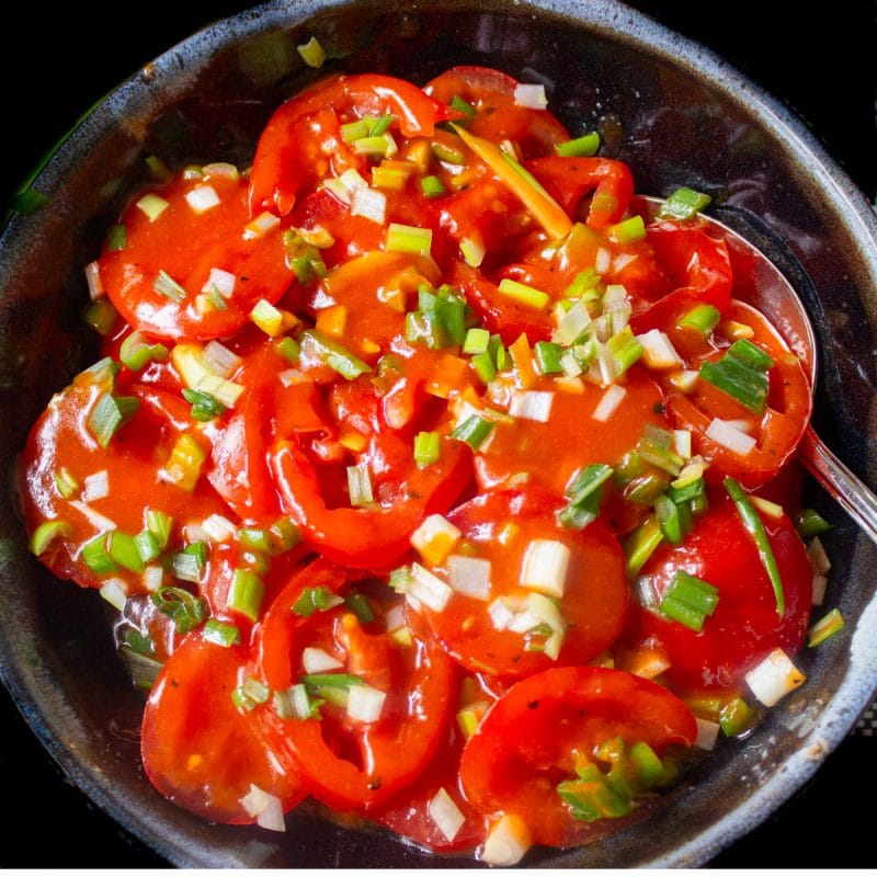 marinated tomato and green onion salad in bowl.