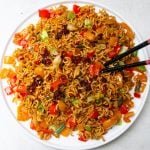Spicy ramen noodles with veggies on plate with chop sticks.