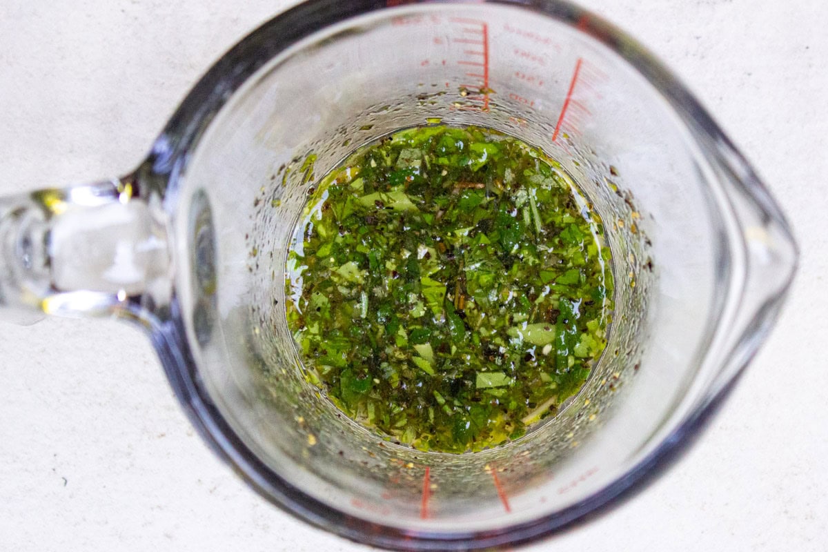 Herb dressing in glass measuring cup.