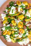 Pan-fried gnocchi with lemon ricotta, nuts and chives on plate.