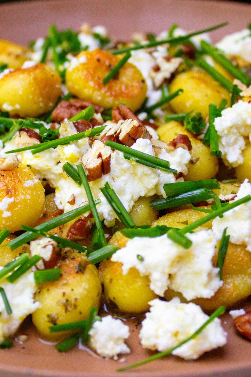 Pan-fried gnocchi with lemon ricotta, nuts and chives on plate.