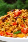 Spicy ramen noodles with veggies on plate with chop sticks.